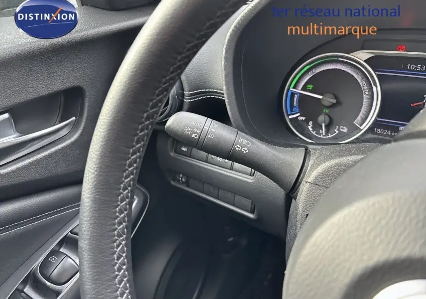 Vue rapprochée du tableau de bord et volant noir du Nissan Juke gris perle hybride avec compteur digital et commandes intégrées.