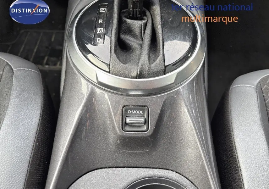 Gros plan sur la console centrale grise perle métallisée du Nissan Juke 2024, avec levier de boîte auto et bouton D-MODE.