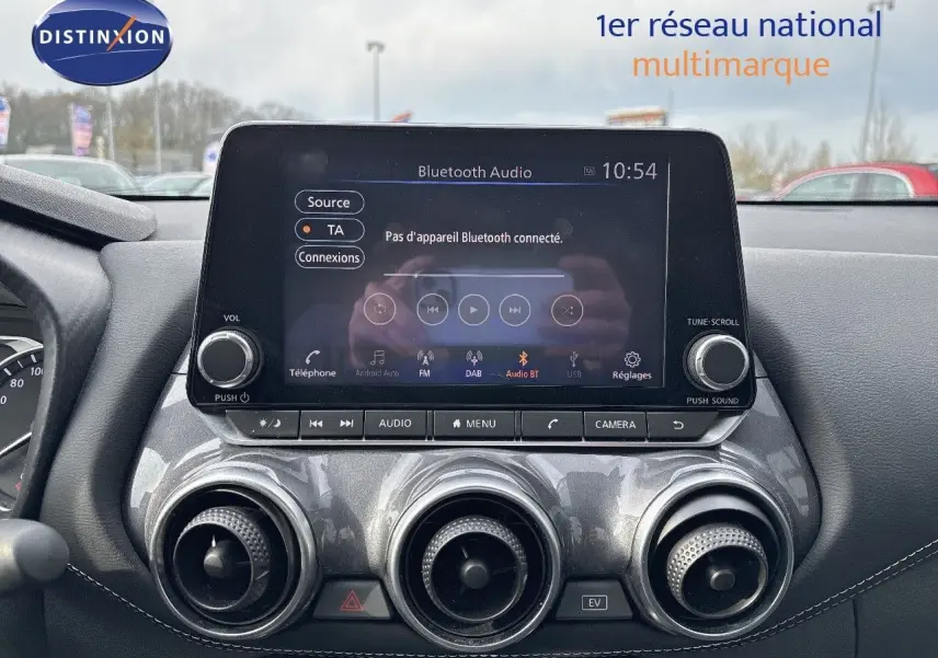 Vue rapprochée de la console centrale du Nissan Juke 2024 gris perle, avec écran tactile et commandes circulaires d’aération.