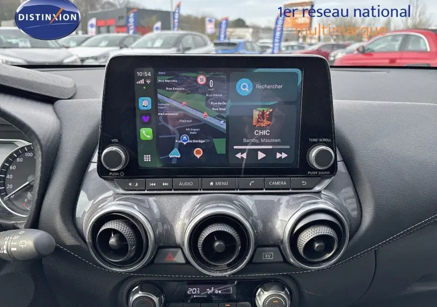 Tableau de bord du Nissan Juke 2024 gris perle, vue frontale centrée sur l'écran tactile et commandes de climatisation.