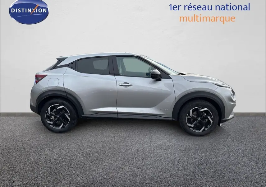 Profil droit du Nissan Juke 1.6 HEV N-Connecta gris perle métal avec jantes noires bicolores sur fond neutre.