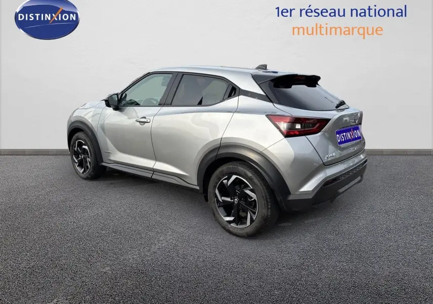 Nissan Juke gris perle métal vu en 3/4 arrière côté gauche, avec jantes noires et toit noir contrasté.
