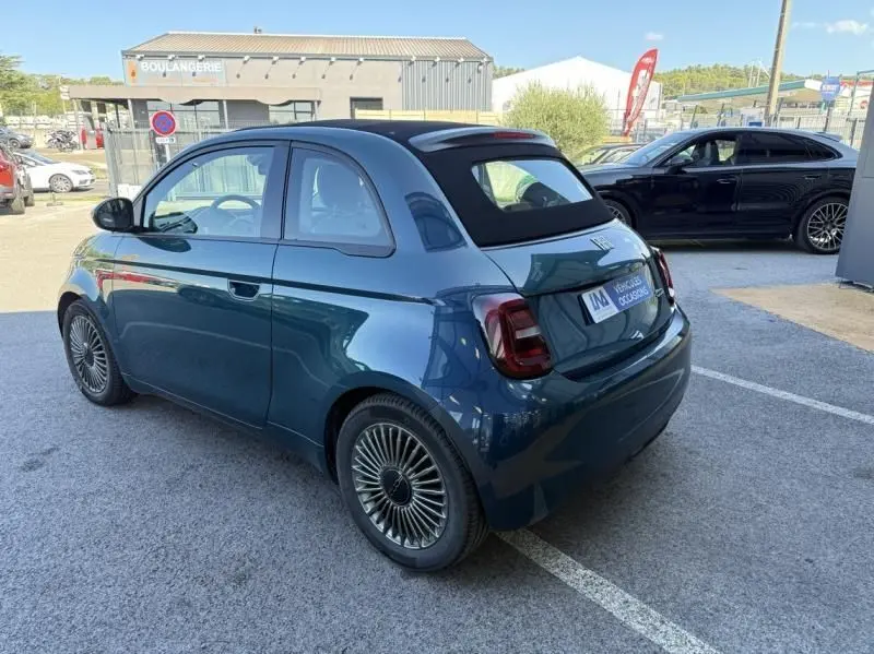 Vue 3/4 arrière droite d'une FIAT 500C électrique 2021 vert foncé métallisé avec toit noir et jantes stylisées.
