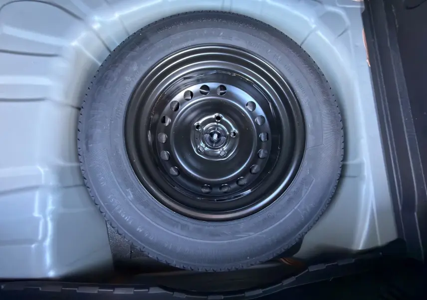 Gros plan sur la roue de secours noire dans le coffre du Renault Captur 2024 gris Cassiopée toit noir.