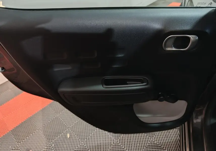 Vue intérieure de la porte arrière droite gris foncé de la Citroën C3 2024 avec poignée argentée et manivelle de vitre.
