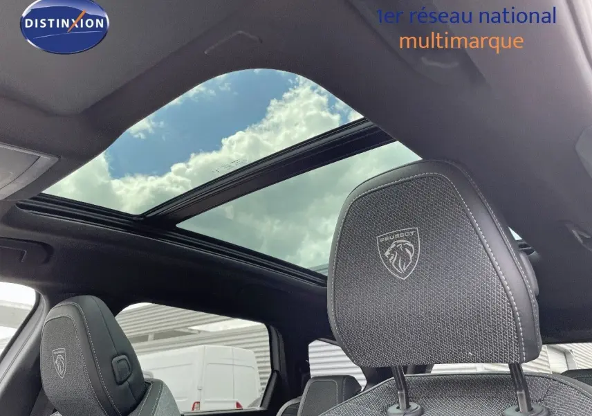 Intérieur du Peugeot 5008 Hybrid 2025 avec toit panoramique et appuie-tête avant brodé au logo Peugeot.
