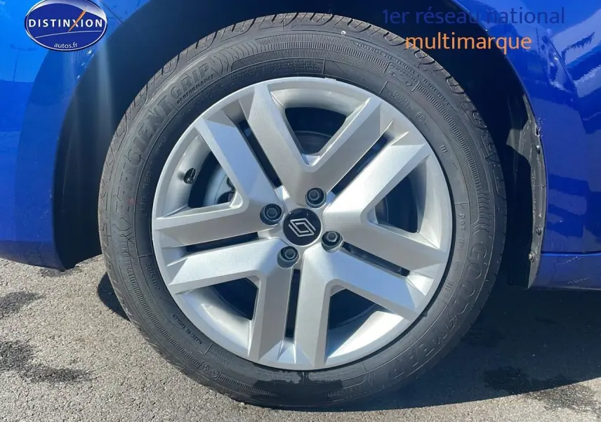 Gros plan sur la roue avant gauche avec jante argentée de la Renault Clio V bleu iron visible côté gauche.