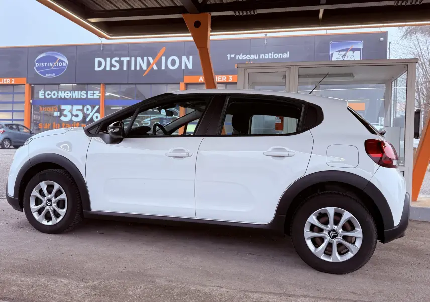 Profil côté gauche d'une Citroën C3 blanche 5 portes, avec jantes alliage et protections noires autour des roues.