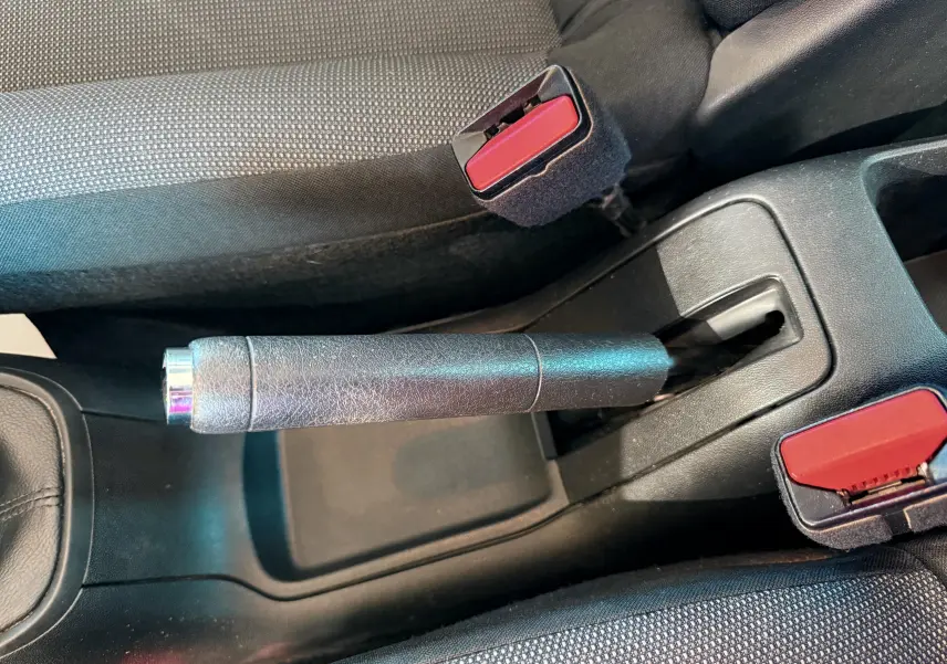 Vue rapprochée de la poignée de frein à main et des ceintures de sécurité rouges dans l'habitacle gris noir d'une Citroën C3.