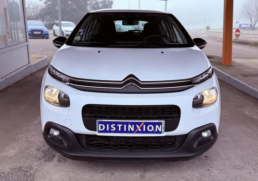 Vue avant d'une Citroën C3 blanche 2017 avec phares allumés et calandre noire distinctive.