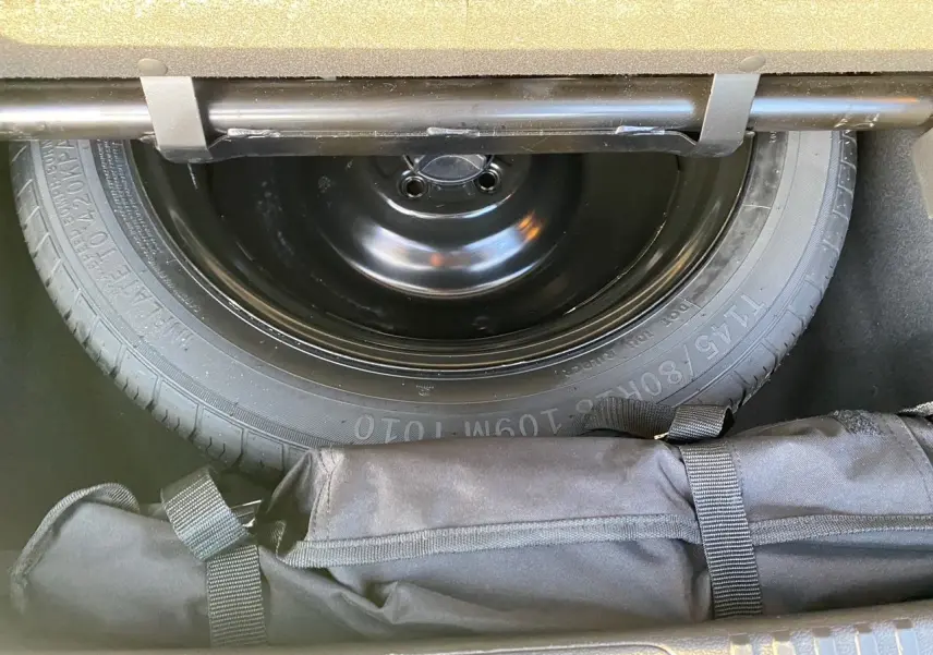 Gros plan sur la roue de secours et le rangement sous le coffre du Renault Espace blanc nacré 2025.