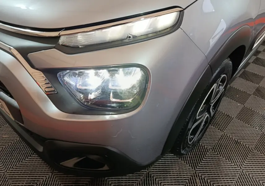 Gros plan sur l'avant droit gris clair de la Citroën C3 2024, mettant en valeur les phares LED et la roue au design distinctif.
