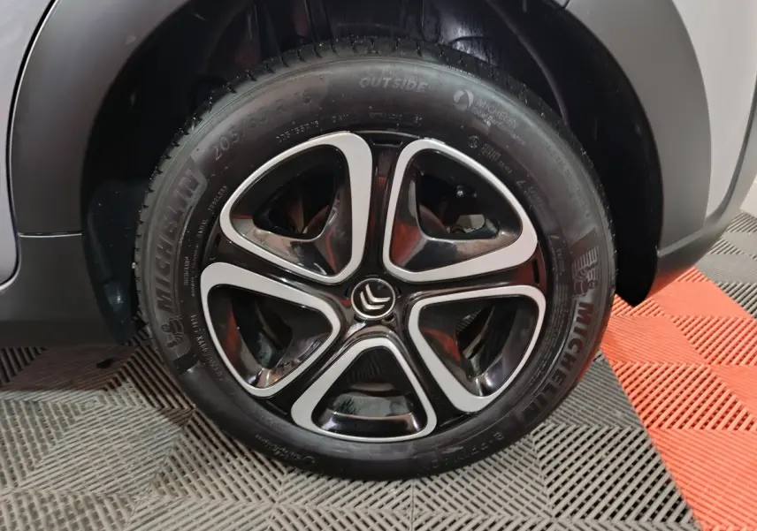 Gros plan sur la roue avant droite grise claire d'une Citroën C3 2024 avec jante alliage noire et argentée distinctive.