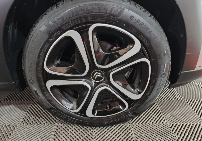 Gros plan sur la roue avant droite gris clair d'une Citroën C3 2024 avec jante noire et argentée au design distinctif.