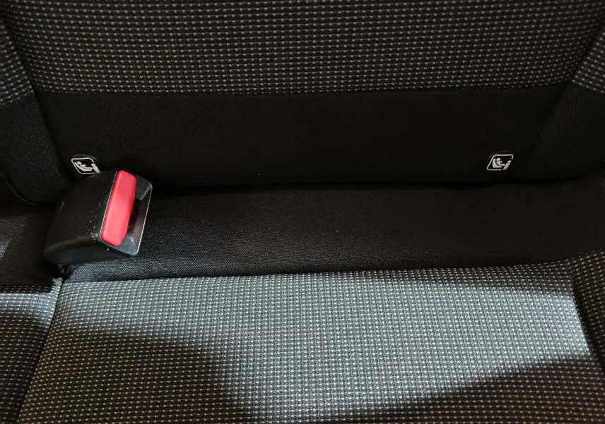 Gros plan sur la banquette arrière en tissu gris à motifs, avec boucle de ceinture de sécurité rouge visible.