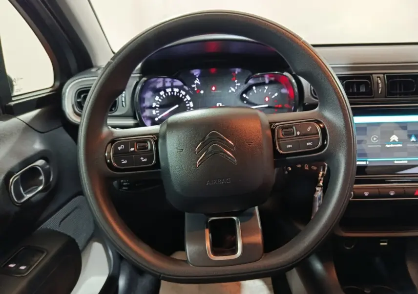 Vue rapprochée du volant multifonctions noir et du tableau de bord numérique de la Citroën C3 2024 gris clair.