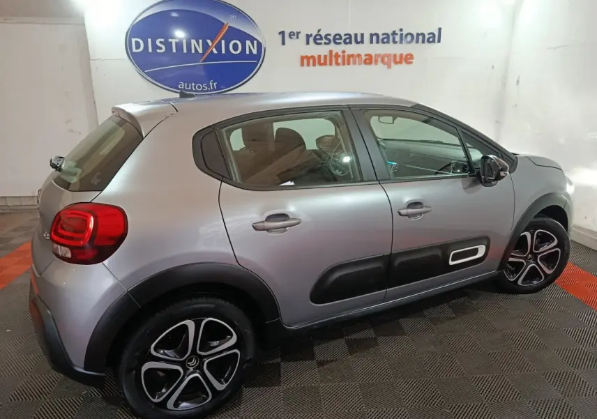 Vue côté droit en 3/4 arrière d'une Citroën C3 gris clair avec protections latérales noires et jantes alliage bicolores.