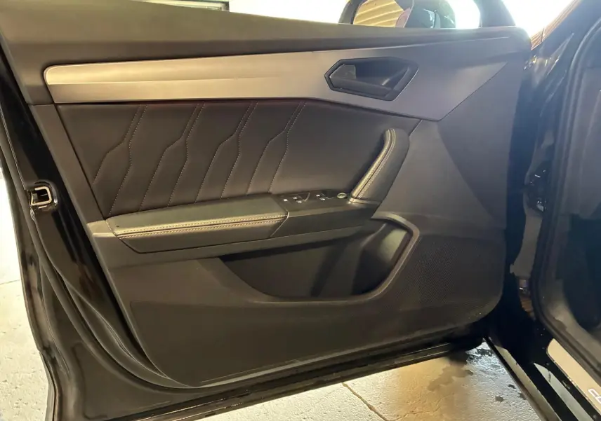 Vue intérieure de la porte avant gauche noire du CUPRA Formentor 2022 avec surpiqûres et commandes de vitres.