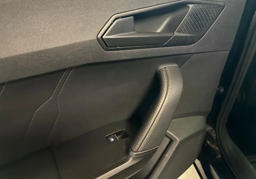 Gros plan sur la poignée intérieure côté gauche de la porte noire du CUPRA Formentor 2.0 TDI avec surpiqûres cuivrées.