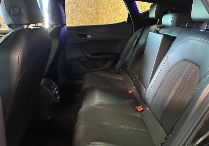 Vue intérieure arrière droite du CUPRA Formentor noir, montrant les sièges en tissu et cuir avec accoudoir central relevé.