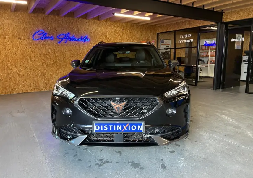 Vue frontale d'une CUPRA Formentor noire 2022 avec calandre marquée et logo cuivré, dans un garage moderne.