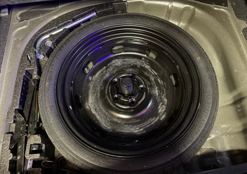 Vue plongeante sur la roue de secours noire et les outils de bord dans le coffre d'une CUPRA Formentor 2.0 TDI 150 V.