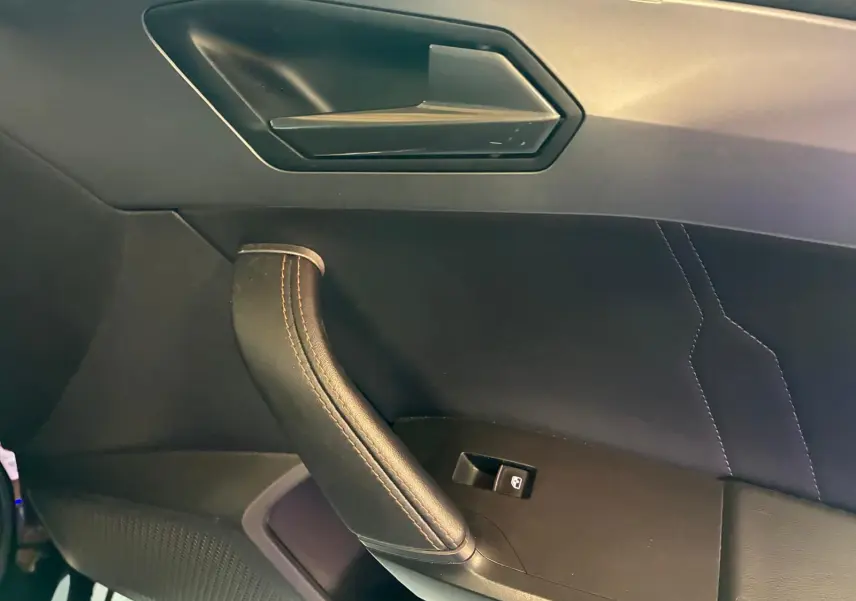 Détail de la poignée de porte côté passager du CUPRA Formentor noir avec surpiqûres cuivrées et bouton de commande de vitre.