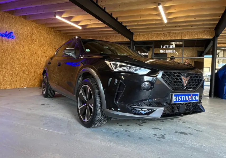 Vue 3/4 avant droite d'un CUPRA Formentor noir 2022 avec jantes alu et calandre distinctive en intérieur d'atelier.