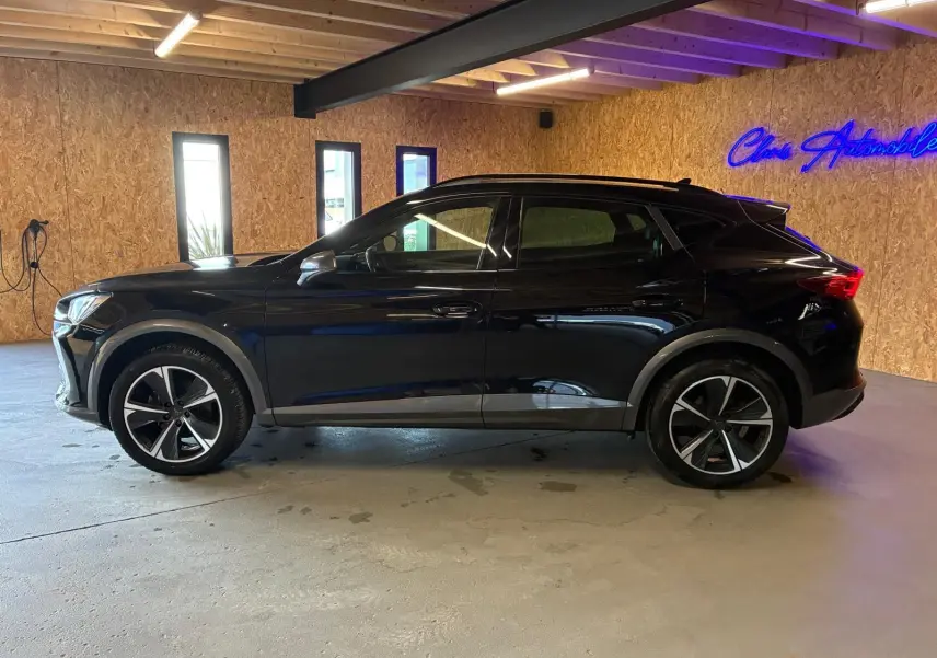 Vue de profil côté gauche d'un CUPRA Formentor noir 2022 avec jantes alu et toit noir piano dans un garage.