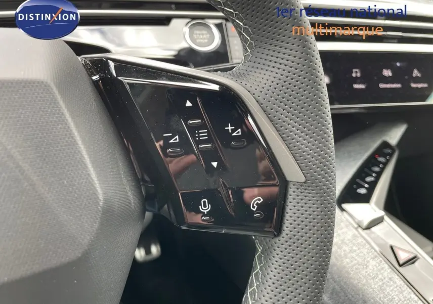 Gros plan sur les commandes tactiles gauche du volant perforé du Peugeot 5008 Hybrid blanc Okenite 2025.