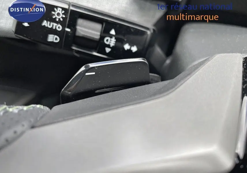 Gros plan sur la commande de feux et le levier de vitesse au volant d'un Peugeot 5008 HYBRID blanc et toit noir.