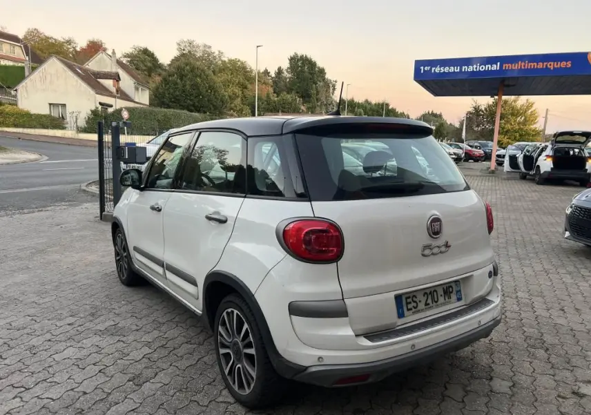 Vue 3/4 arrière droite d'une FIAT 500L 2017 bi-color blanc avec toit noir, stationnée sur un parking pavé.