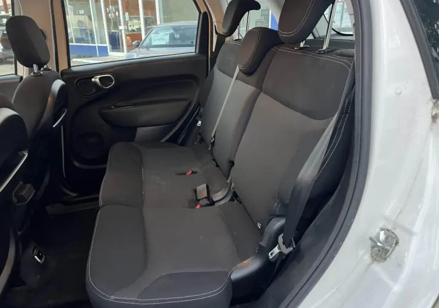 Vue intérieure côté droit montrant la banquette arrière noire de la Fiat 500L 2017 avec ceinture de sécurité et porte ouverte.