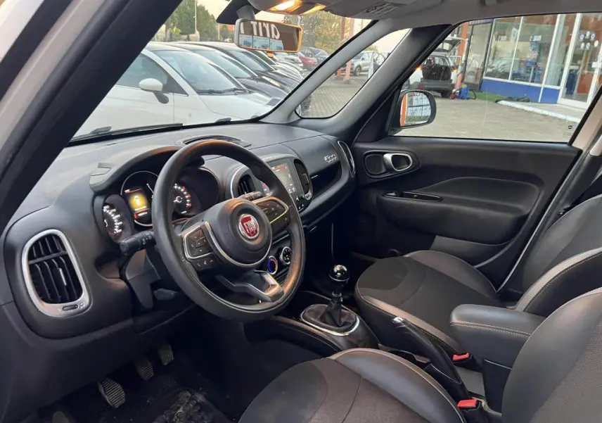 Intérieur avant droit d'une Fiat 500L 2017 avec tableau de bord noir, volant multifonction et levier de vitesse manuel.