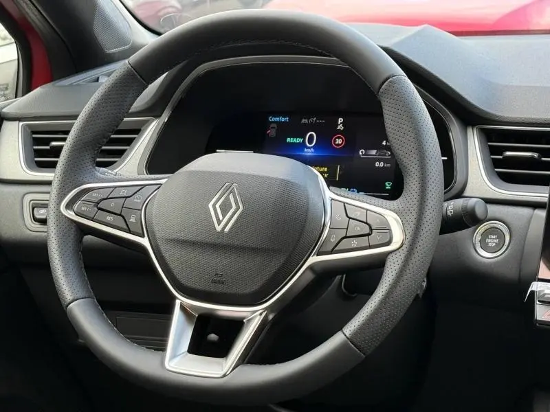 Vue rapprochée du volant multifonction noir de la Renault Captur 2025 avec tableau de bord numérique et bouton start/stop.