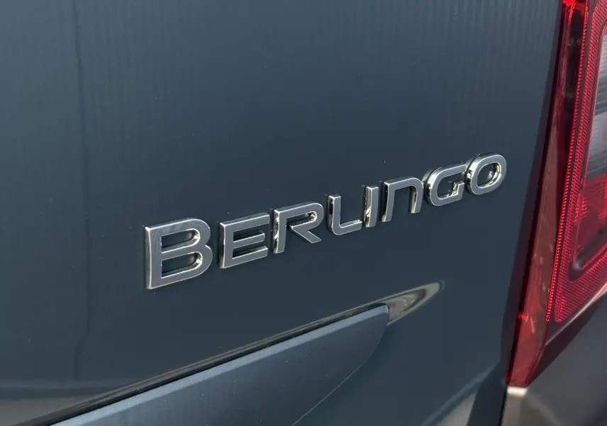 Gros plan sur l'arrière droit bleu métallisé du Citroën Berlingo avec logo et feu arrière rouge visible.