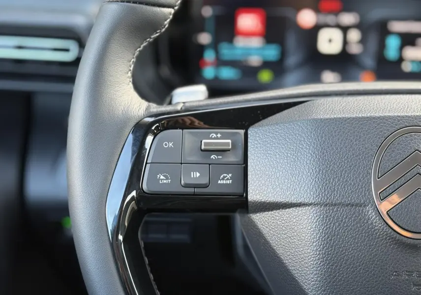 Gros plan sur le volant cuir multifonctions du Citroën Berlingo Multispace bleu, avec commandes intégrées et logo central visible.