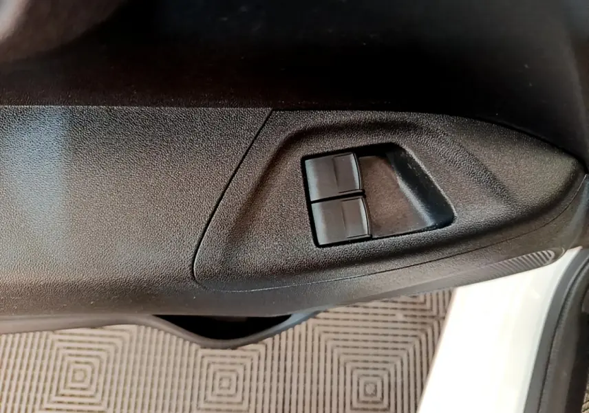 Gros plan sur les commandes des vitres électriques côté conducteur d’une Citroën C1 blanche, porte ouverte.