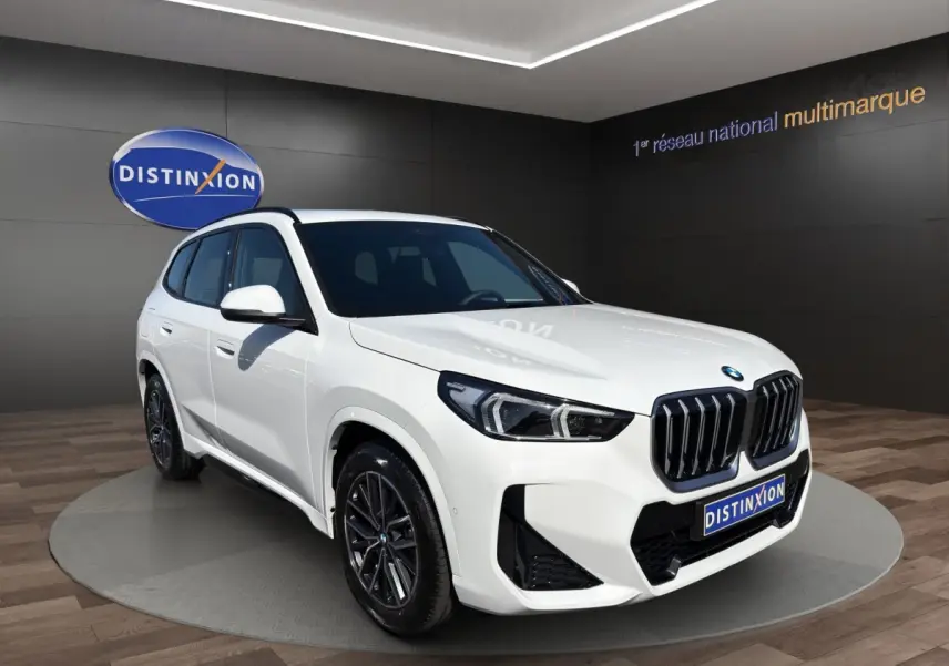BMW X1 sDrive20d blanc vue de profil côté gauche avec jantes noires en showroom intérieur