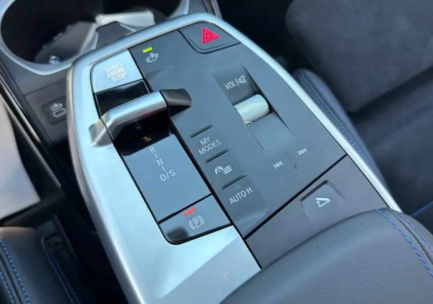 Vue rapprochée de la console centrale noire et argentée du BMW X1 M SPORT 2025 avec surpiqûres bleues.