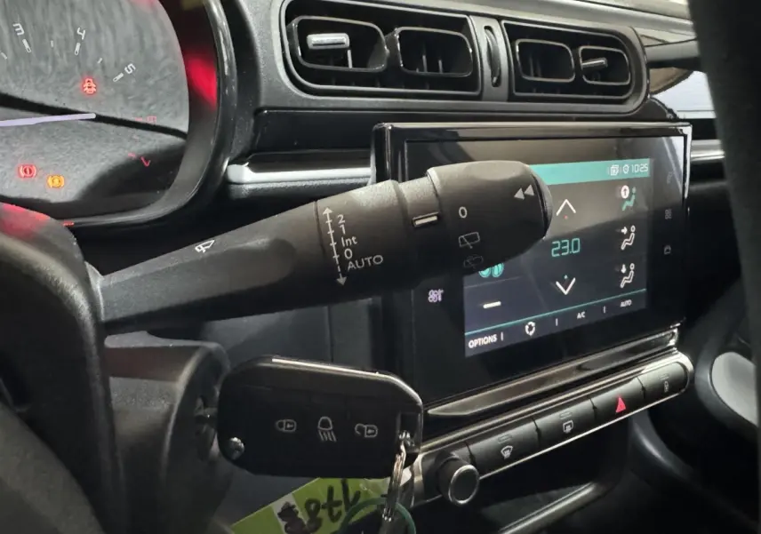 Vue rapprochée de l'intérieur de la Citroën C3 bleu, montrant le commodo d'essuie-glace et l'écran tactile central.