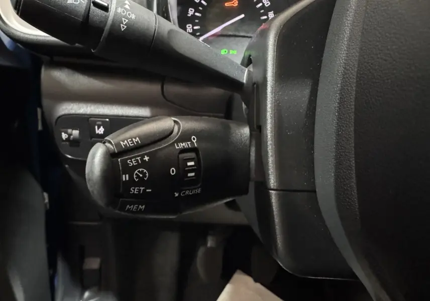Gros plan sur la commande de régulateur de vitesse à gauche du volant dans l’habitacle d’une Citroën C3 bleu 2018.