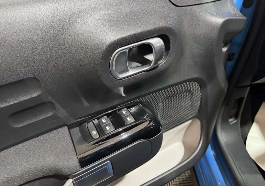 Gros plan sur la porte avant gauche bleu de la Citroën C3 2018, avec commandes de vitres et poignée intérieure chromée.