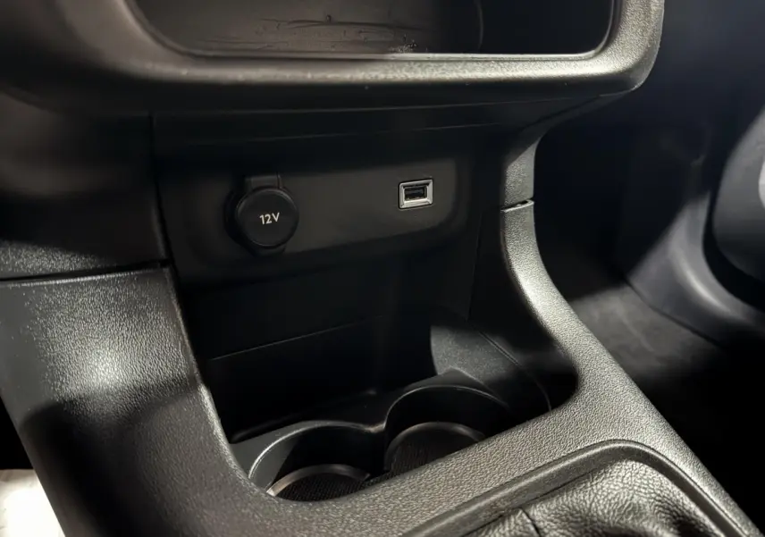 Vue rapprochée de la console centrale noire de la Citroën C3 avec prise 12V et port USB visibles.