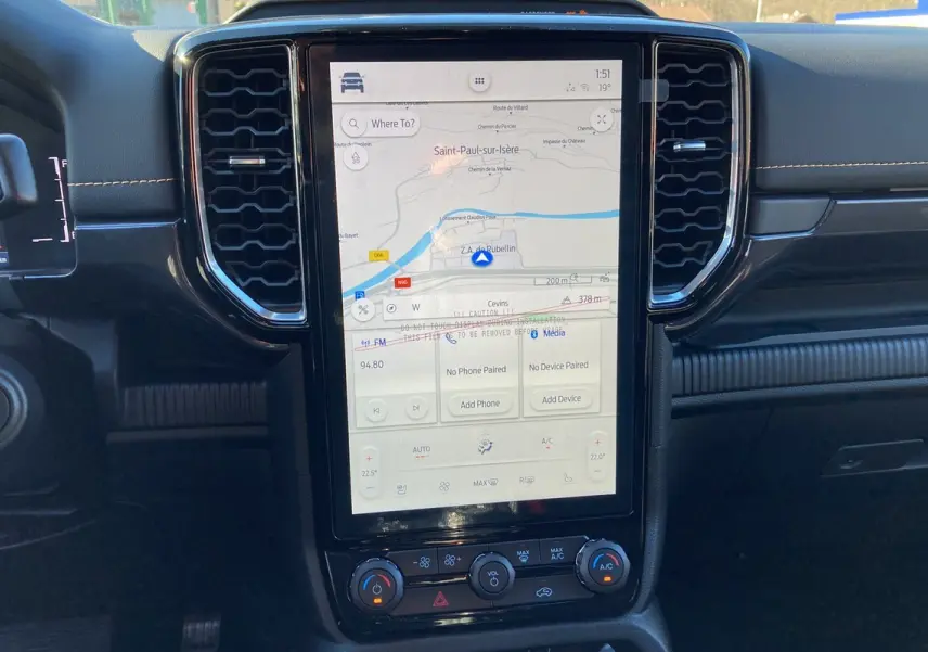 Vue rapprochée de la console centrale du Ford Ranger blanc glacier 2025, écran tactile GPS et commandes climatisation visibles.
