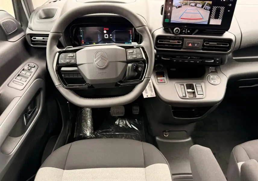Vue intérieure centrée sur le volant et tableau de bord du Citroën Berlingo gris Artense avec écran tactile et caméra de recul.