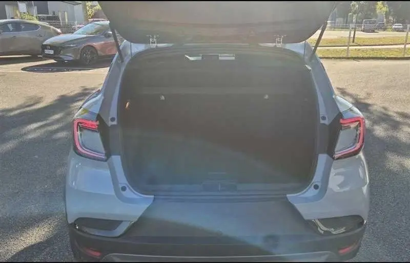 Vue arrière du Renault Captur E-Tech hybride gris Rafale avec coffre ouvert, mettant en valeur ses feux LED distinctifs.