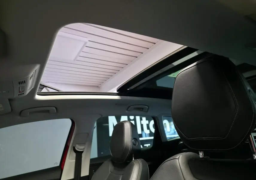 Toit ouvrant panoramique ouvert vu de l'intérieur avant d'un Skoda Karoq rouge avec sièges cuir noirs.