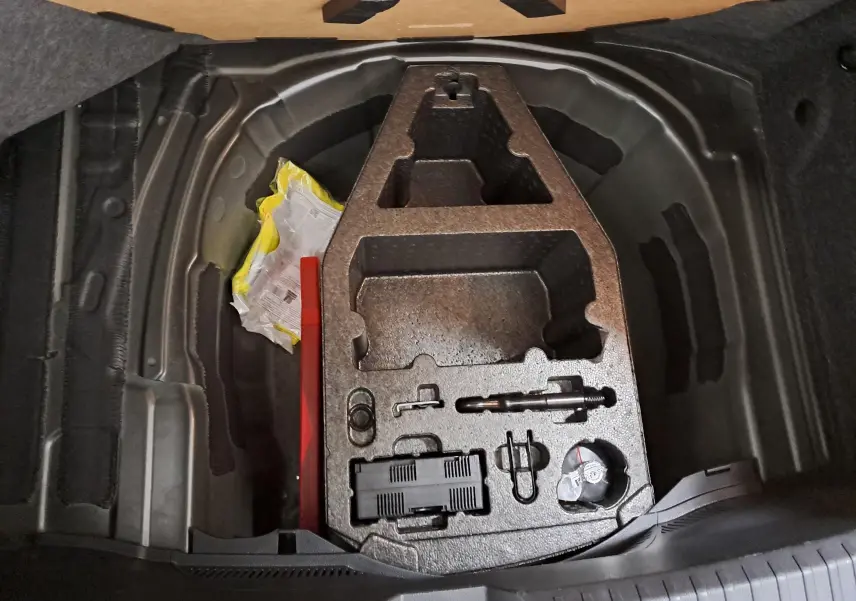 Coffre ouvert du SEAT Ibiza 2024 noir minuit, vue plongeante sur le rangement sous plancher avec outils et accessoires.