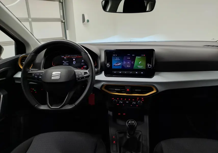 Vue intérieure frontale du tableau de bord de la SEAT Ibiza 2024 noir minuit avec écran tactile et levier de vitesses manuel.